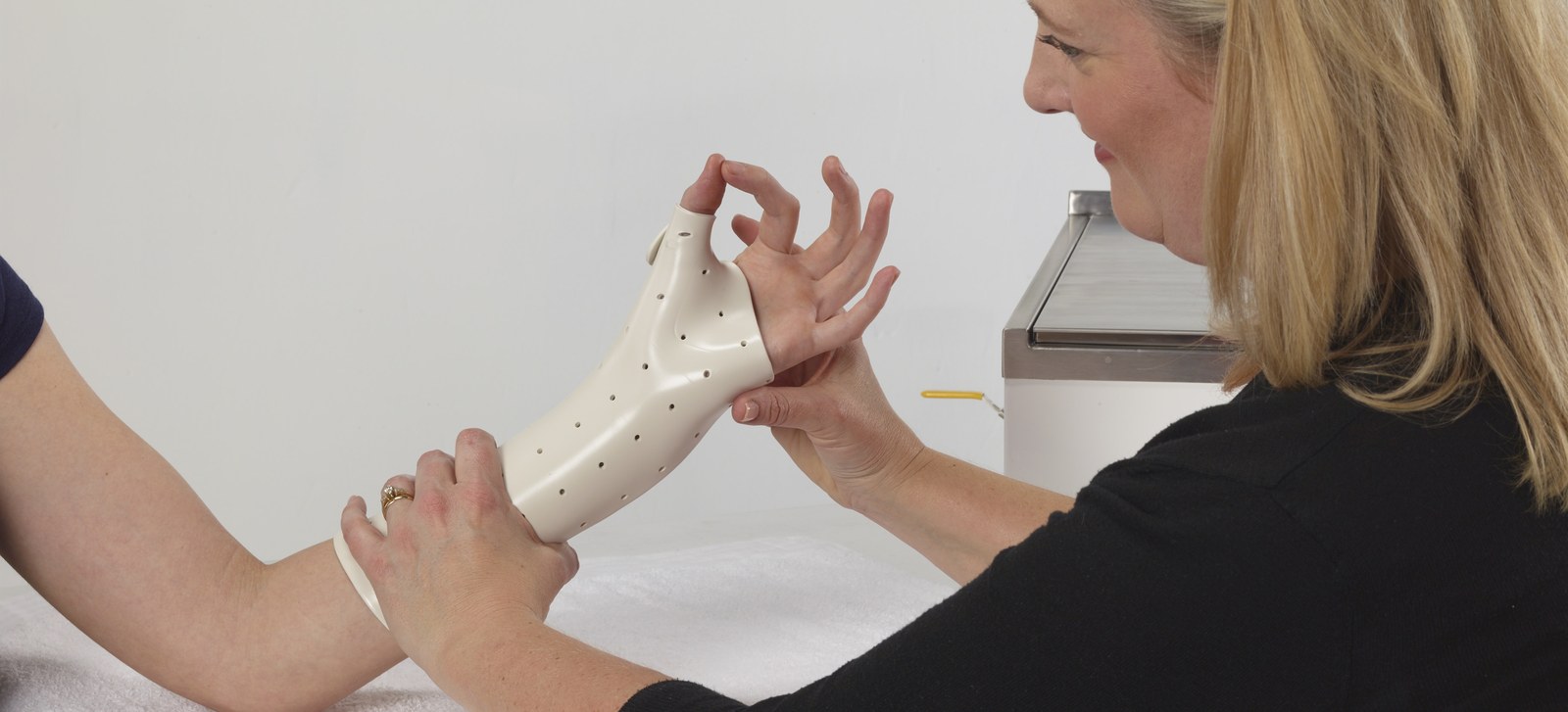 Una terapista modella un tutore termoplastico Manosplint sul polso di una paziente